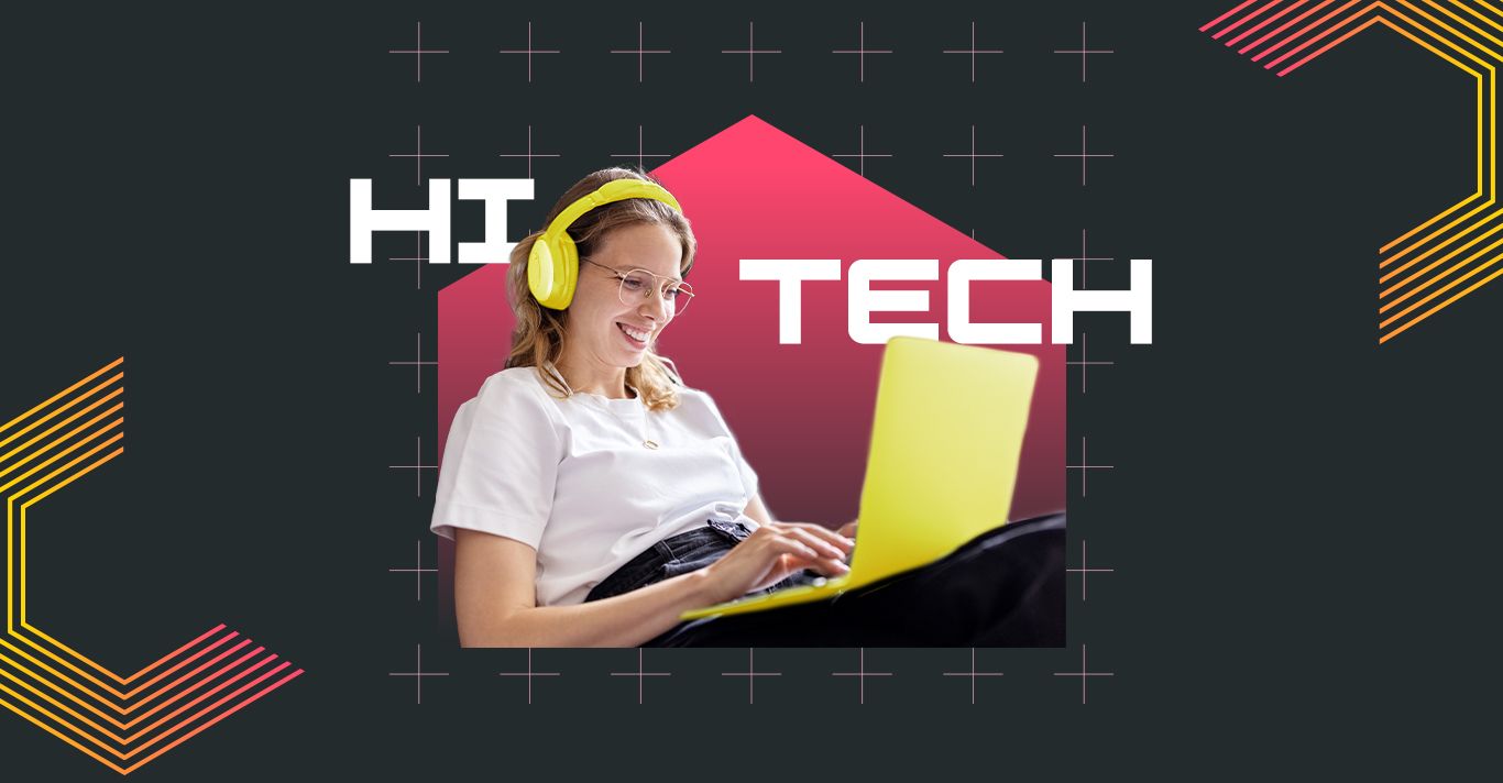 HI TECH. Young adult sits using their laptop smiling at the screen on a dark grey background.